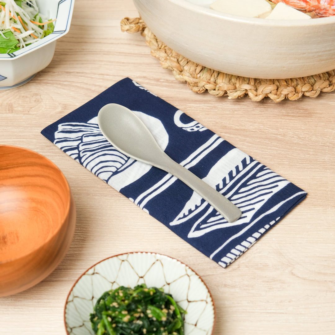 Japanese ceramic soup spoon placed on indigo tenugui cloth, perfect for serving donabe hot pot and traditional Japanese meals.