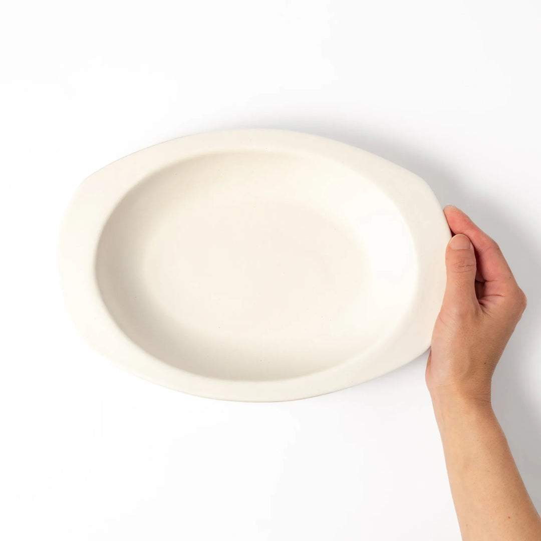 White oval ceramic curry plate with a wide rim and curved sides, designed for smooth scooping and serving of curry, rice, or pasta dishes.