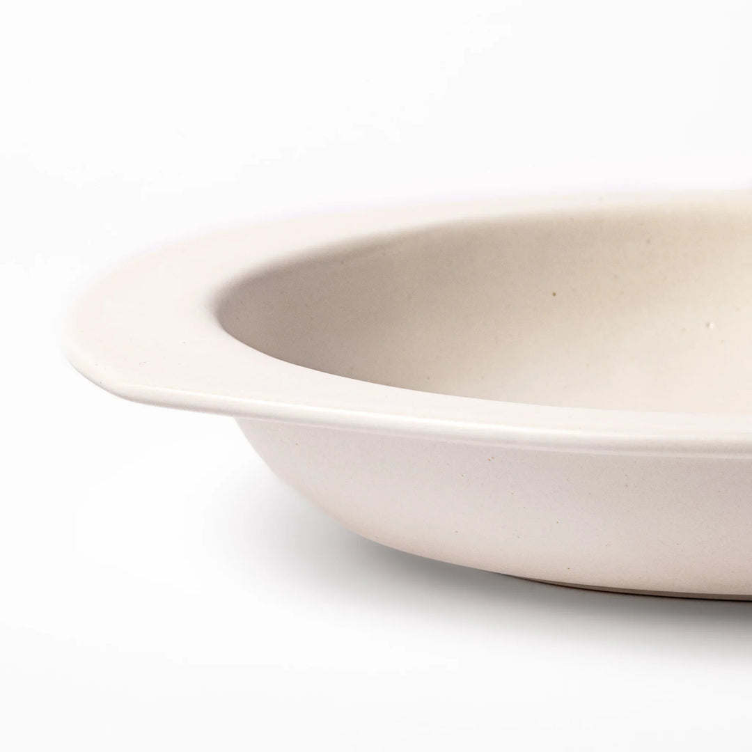 White oval ceramic curry plate with a wide rim and curved sides, designed for smooth scooping and serving of curry, rice, or pasta dishes.