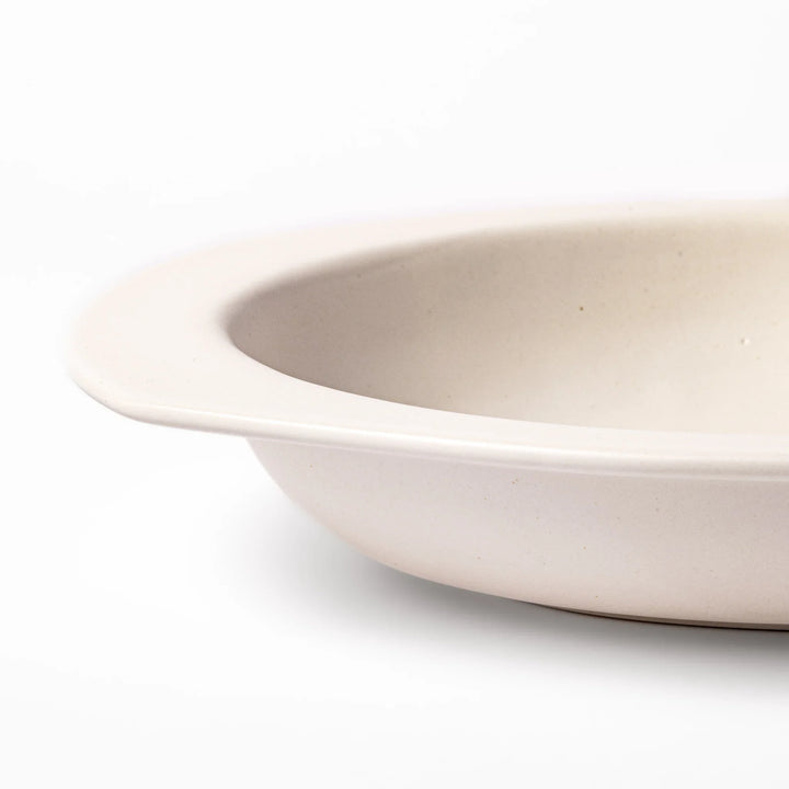 White oval ceramic curry plate with a wide rim and curved sides, designed for smooth scooping and serving of curry, rice, or pasta dishes.