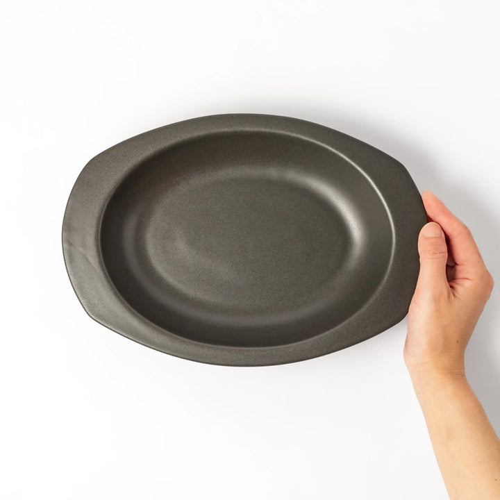 Black oval ceramic curry plate with wide rim and curved edges, designed for effortless scooping and perfect for curry, rice, or pasta dishes.