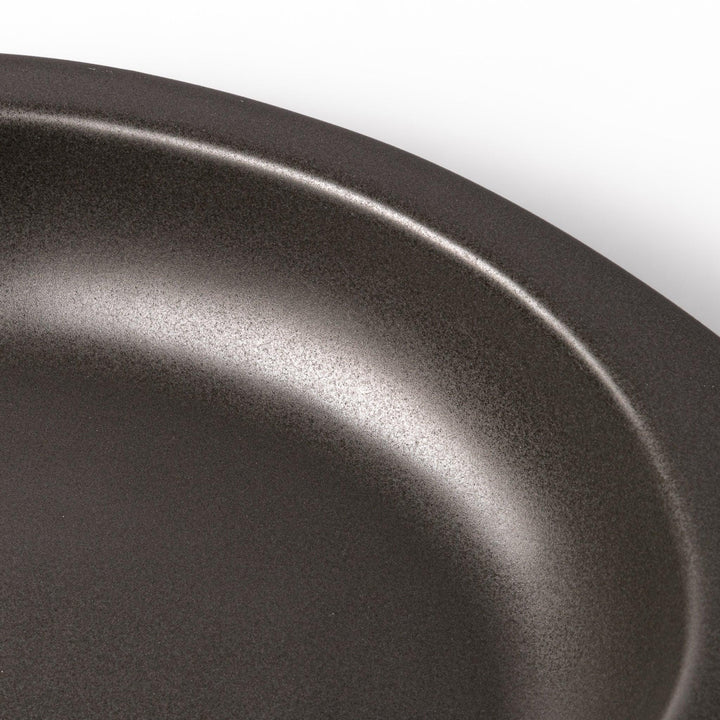 Black oval ceramic curry plate with wide rim and curved edges, designed for effortless scooping and perfect for curry, rice, or pasta dishes.