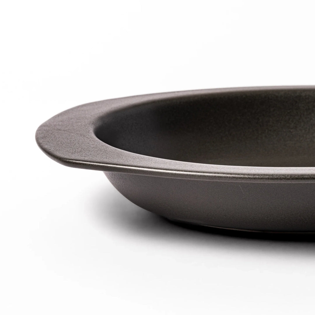 Black oval ceramic curry plate with wide rim and curved edges, designed for effortless scooping and perfect for curry, rice, or pasta dishes.