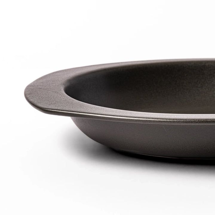 Black oval ceramic curry plate with wide rim and curved edges, designed for effortless scooping and perfect for curry, rice, or pasta dishes.