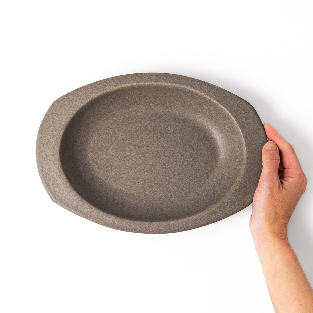 Gray oval ceramic curry plate with gently raised sides and wide rim, designed for easy scooping and serving rice, curry, or stew dishes.