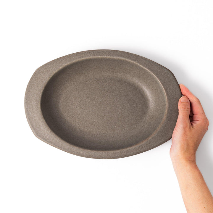 Gray oval ceramic curry plate with gently raised sides and wide rim, designed for easy scooping and serving rice, curry, or stew dishes.