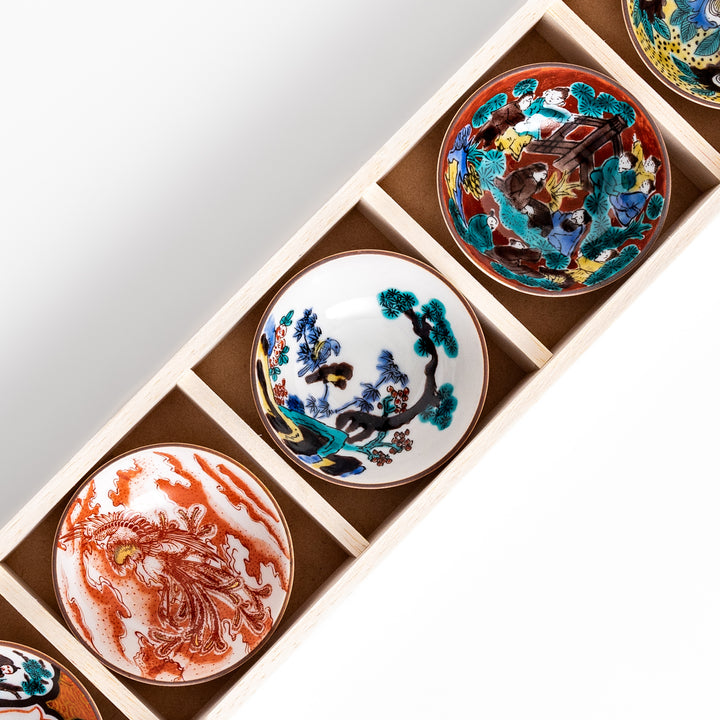 Elegant set of five sake cups with intricate floral and traditional patterns, presented in a wooden box, showcasing timeless Japanese craftsmanship and design.