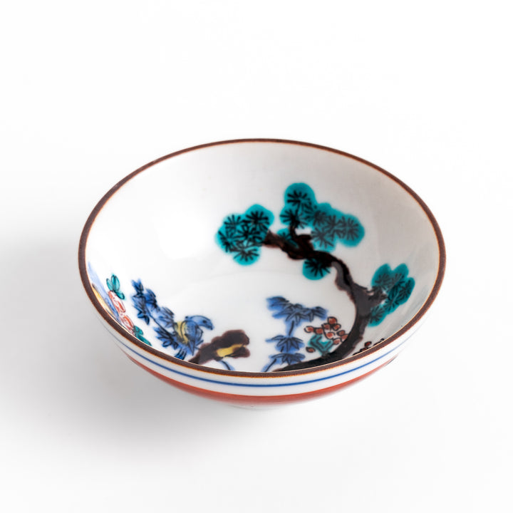 Traditional sake cup showcasing a hand-painted scene of a bird perched on a tree, surrounded by lush greenery, highlighting vibrant colors and Japanese artistry.
