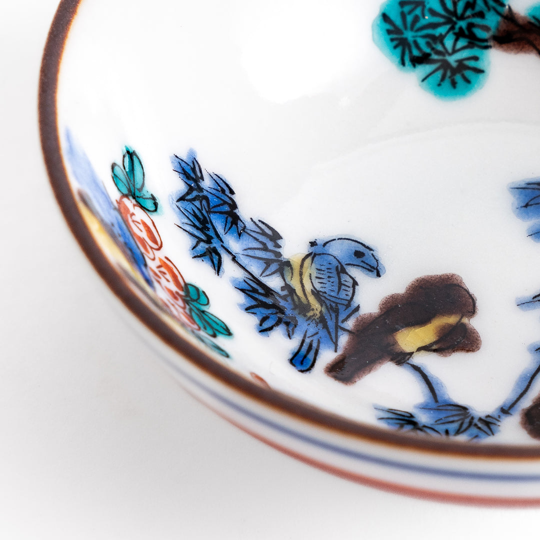 Traditional sake cup showcasing a hand-painted scene of a bird perched on a tree, surrounded by lush greenery, highlighting vibrant colors and Japanese artistry.