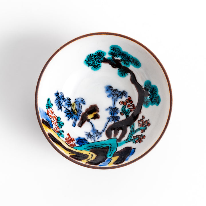 Traditional sake cup showcasing a hand-painted scene of a bird perched on a tree, surrounded by lush greenery, highlighting vibrant colors and Japanese artistry.