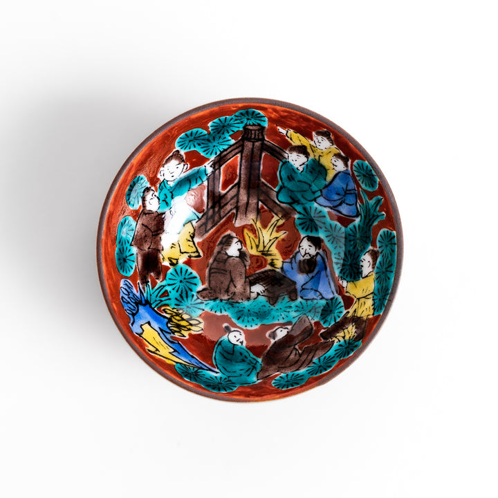Sake cup with a vivid depiction of a historical scene, featuring figures gathered around a fire, set against a colorful, intricate background.