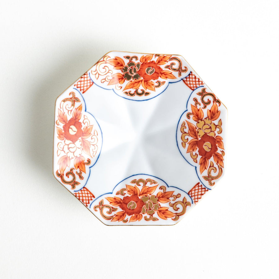 Octagonal plate with ornate orange floral patterns on a white background.
