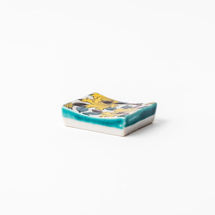 Japanese porcelain chopstick rest with yellow peony and teal leaf motif, hand-painted in traditional Kutani ware style.