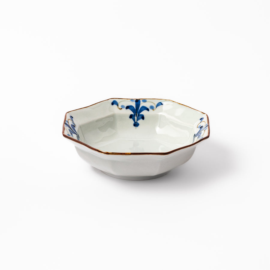White octagonal ceramic bowl with blue floral leaf patterns along the inner rim and a brown-edged border.