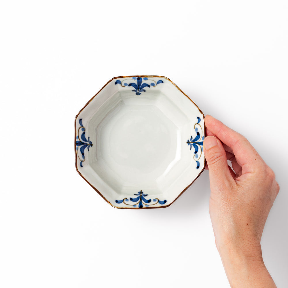 White octagonal ceramic bowl with blue floral leaf patterns along the inner rim and a brown-edged border.