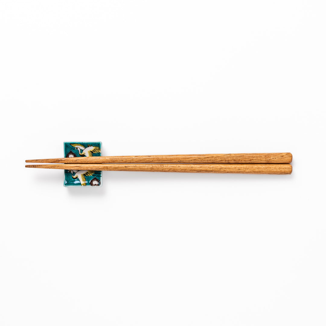 Rectangular Japanese ceramic chopstick rest featuring flying crane motif with teal geometric background and gold accents, symbolizing longevity and elegance in dining.