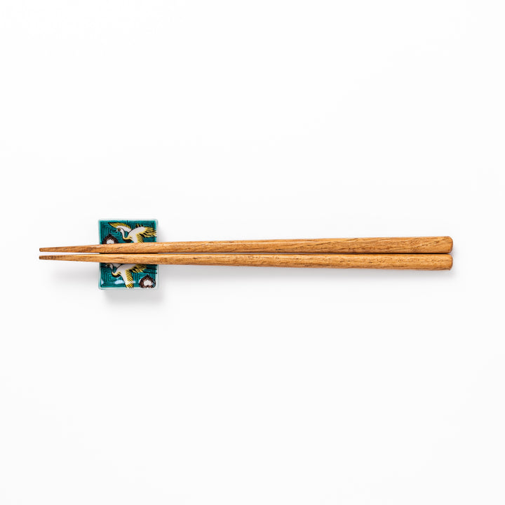 Rectangular Japanese ceramic chopstick rest featuring flying crane motif with teal geometric background and gold accents, symbolizing longevity and elegance in dining.