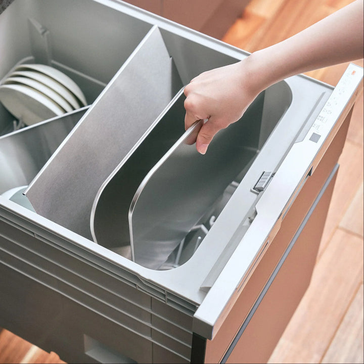 Person placing disassembled stainless steel splatter guard panels into a dishwasher drawer