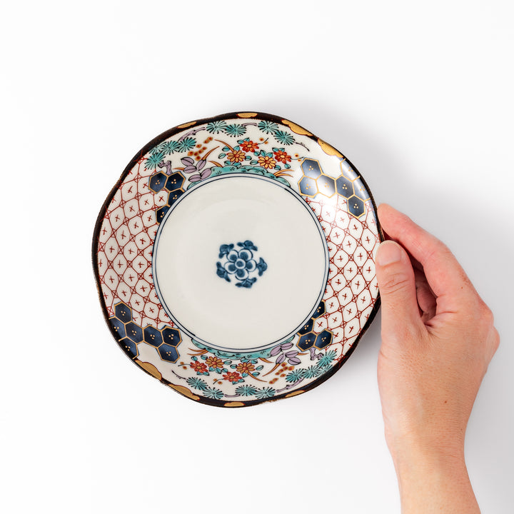 Scalloped Japanese dessert plate with red lattice, navy hexagons, and multicolor floral design, perfect for adding charm to elegant table settings.