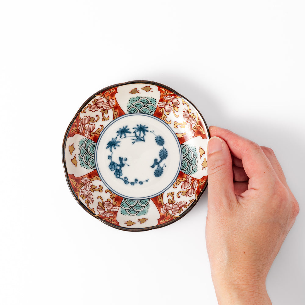 Scalloped edge sauce dish featuring red, blue, and green traditional Japanese motifs with a floral center, perfect for elegant table presentations.