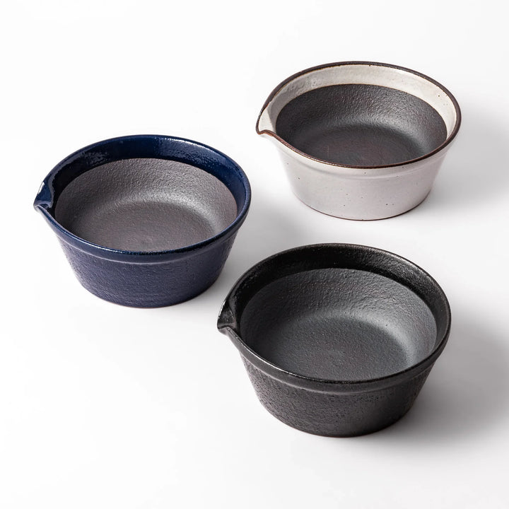 Set of three grooveless ceramic suribachi mortar bowls in black, deep blue, and white, each with a spout and smooth interior for easy grinding.