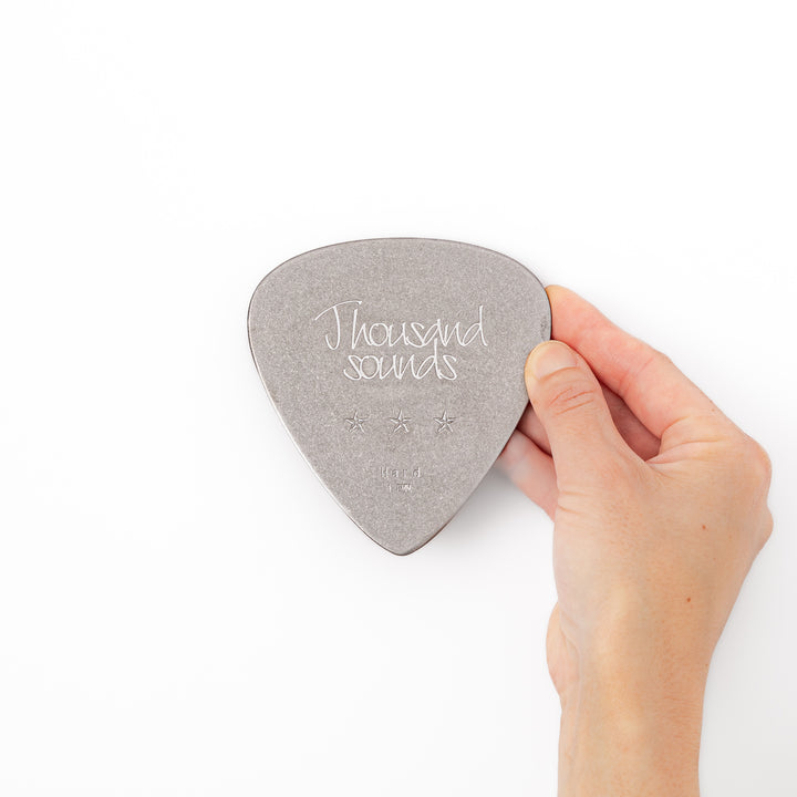 Unique guitar pick shaped metal coaster with vintage matte finish engraved with thousand sounds text and stars