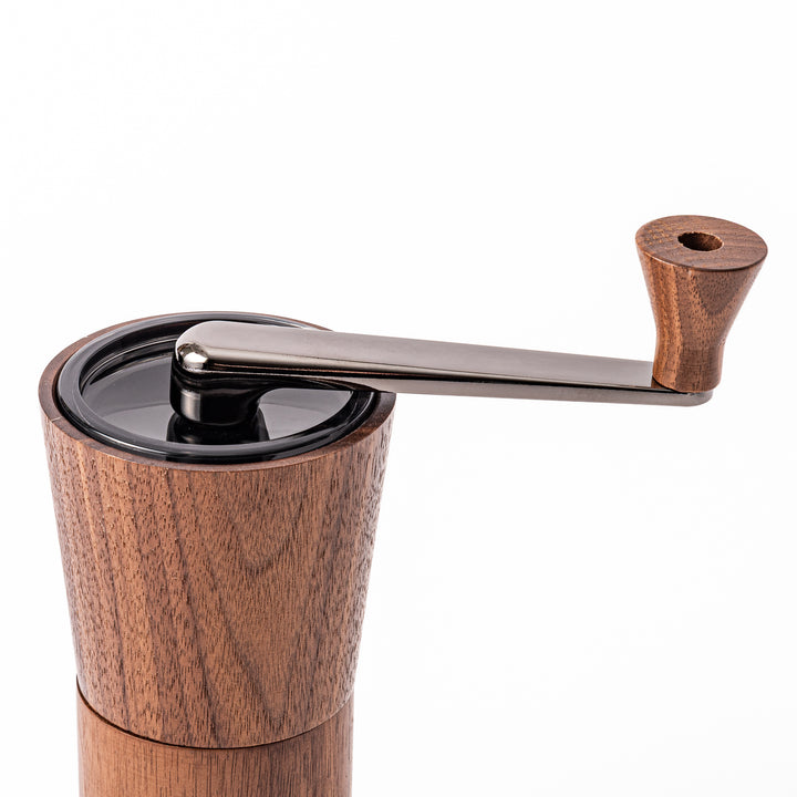 HARIO walnut wood manual coffee grinder with a hand crank, featuring a sleek natural wooden body on a white background