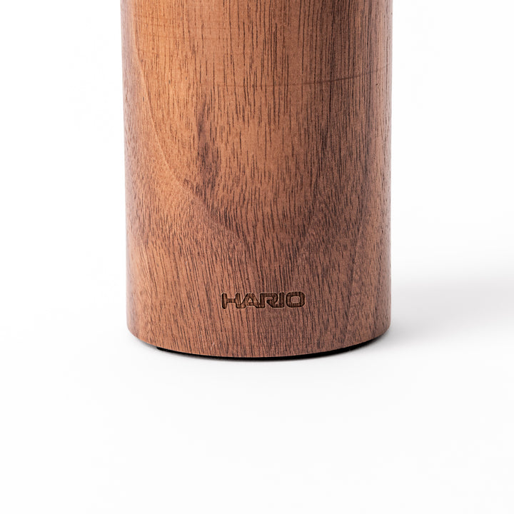 HARIO walnut wood manual coffee grinder with a hand crank, featuring a sleek natural wooden body on a white background