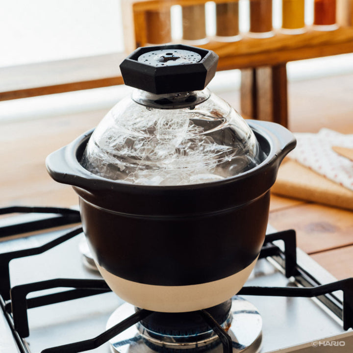 Boiling rice inside hario glass lid donabe clay pot cooker on gas stove top burners traditional kitchenware