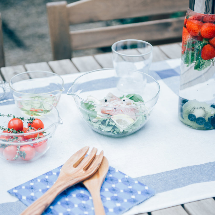 Hario heatproof glass mixing bowls with fresh salad and fruit infused water pitcher on wooden outdoor dining table