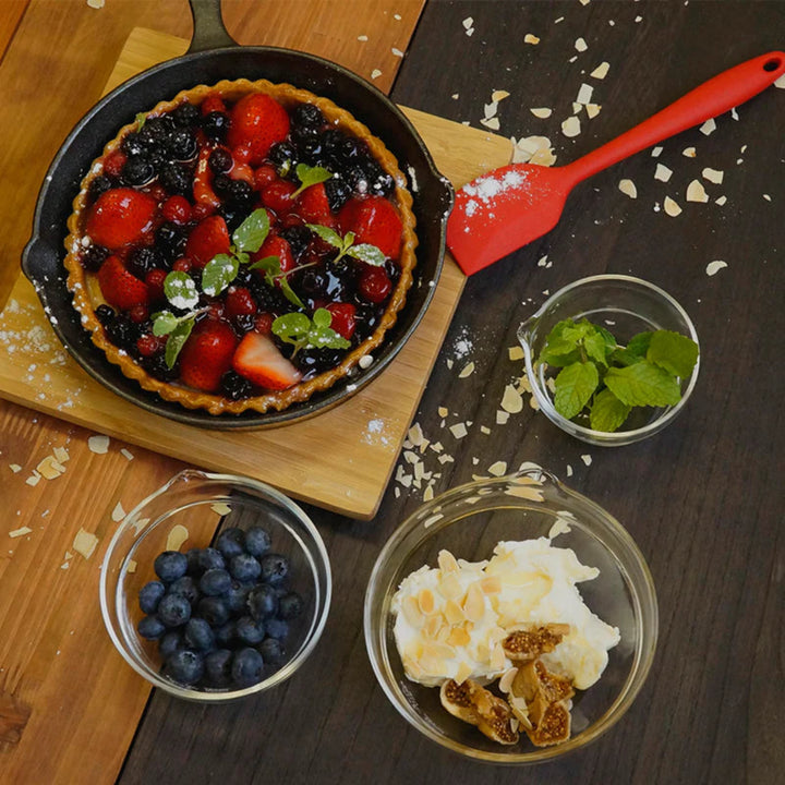 Preparing a berry tart next to hario heatproof glass lip bowls filled with blueberries mint leaves and cream dessert