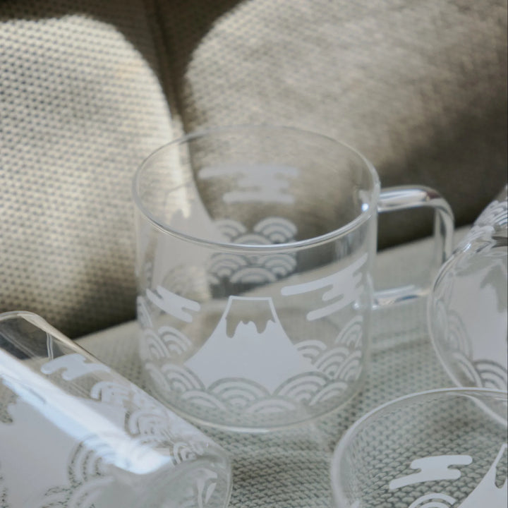 Set of HARIO Mount Fuji thermochromic glass mugs with white traditional Japanese wave patterns on a textured armchair