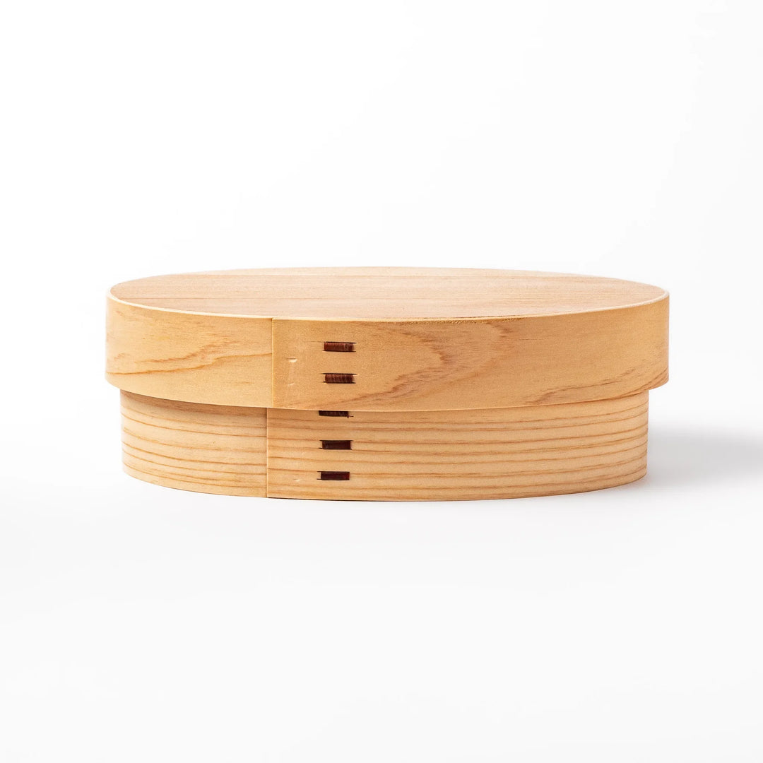 Oval bento box handcrafted from smooth hinoki wood with traditional joinery, offering a lightweight and aromatic way to carry Japanese-style meals.
