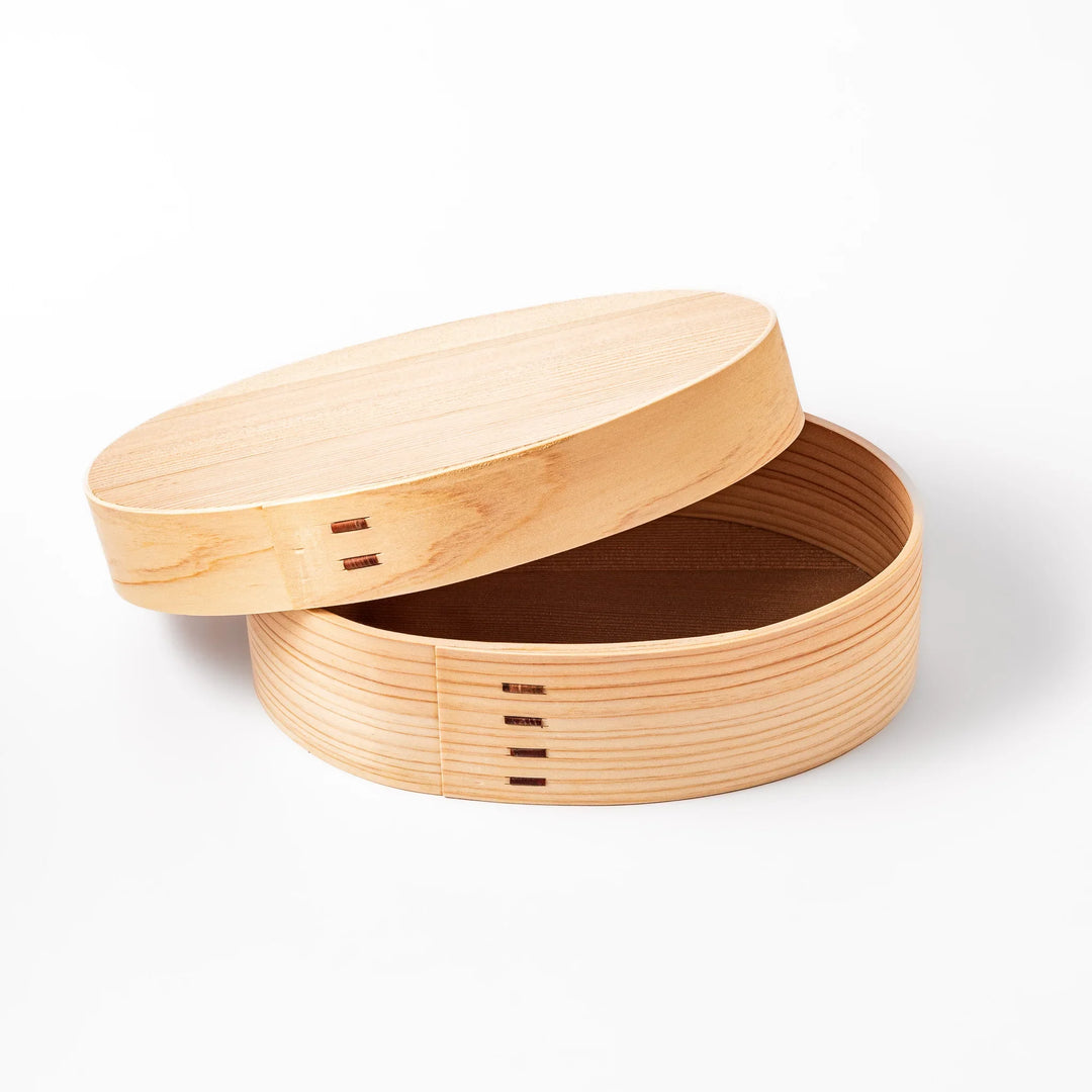 Oval bento box handcrafted from smooth hinoki wood with traditional joinery, offering a lightweight and aromatic way to carry Japanese-style meals.
