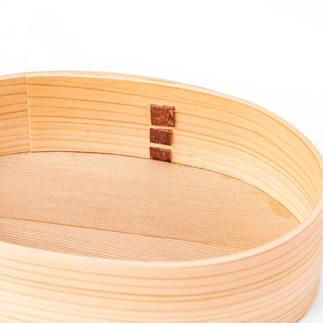 Oval bento box handcrafted from smooth hinoki wood with traditional joinery, offering a lightweight and aromatic way to carry Japanese-style meals.
