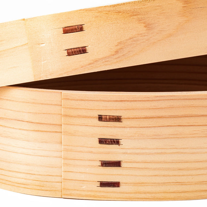 Oval bento box handcrafted from smooth hinoki wood with traditional joinery, offering a lightweight and aromatic way to carry Japanese-style meals.
