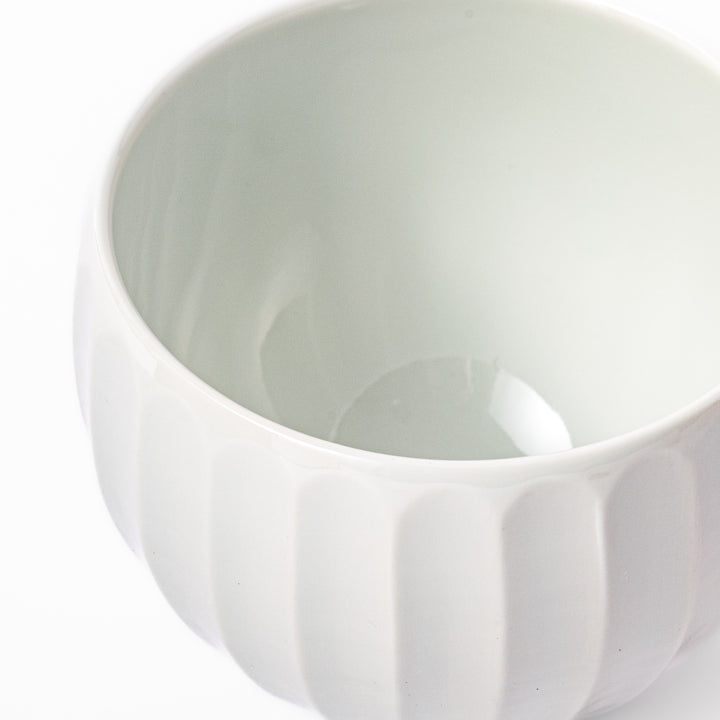 White teacup with vertical petal-like grooves and glossy finish, ideal for serving hot tea with a refined and modern aesthetic.