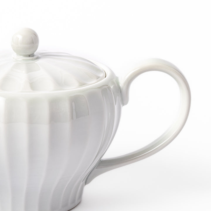 White teapot with vertical petal-inspired ridges and a round lid, perfect for a refined and elegant tea presentation.