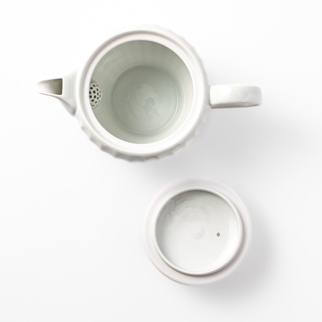 White teapot with vertical petal-inspired ridges and a round lid, perfect for a refined and elegant tea presentation.