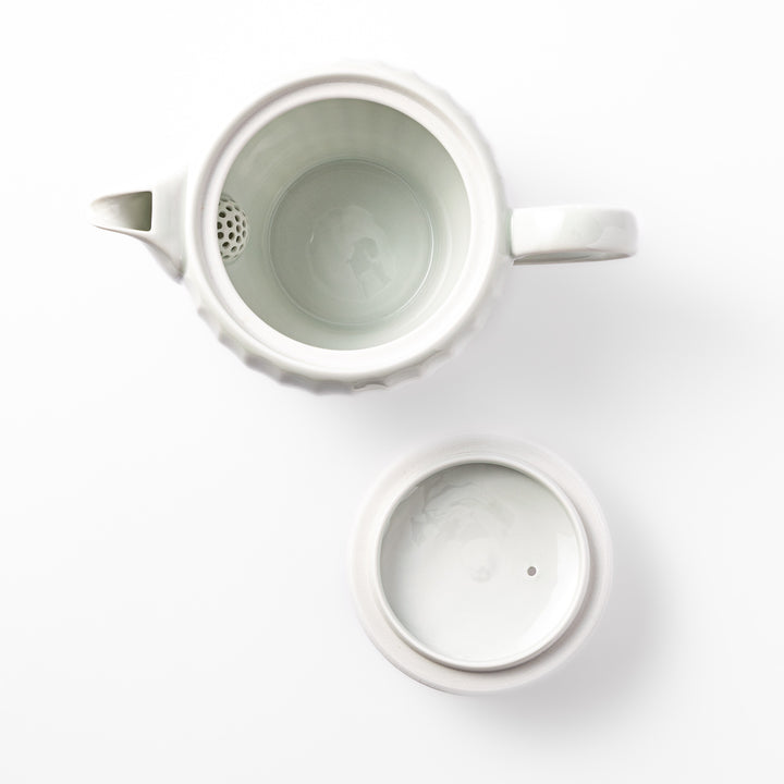 White teapot with vertical petal-inspired ridges and a round lid, perfect for a refined and elegant tea presentation.