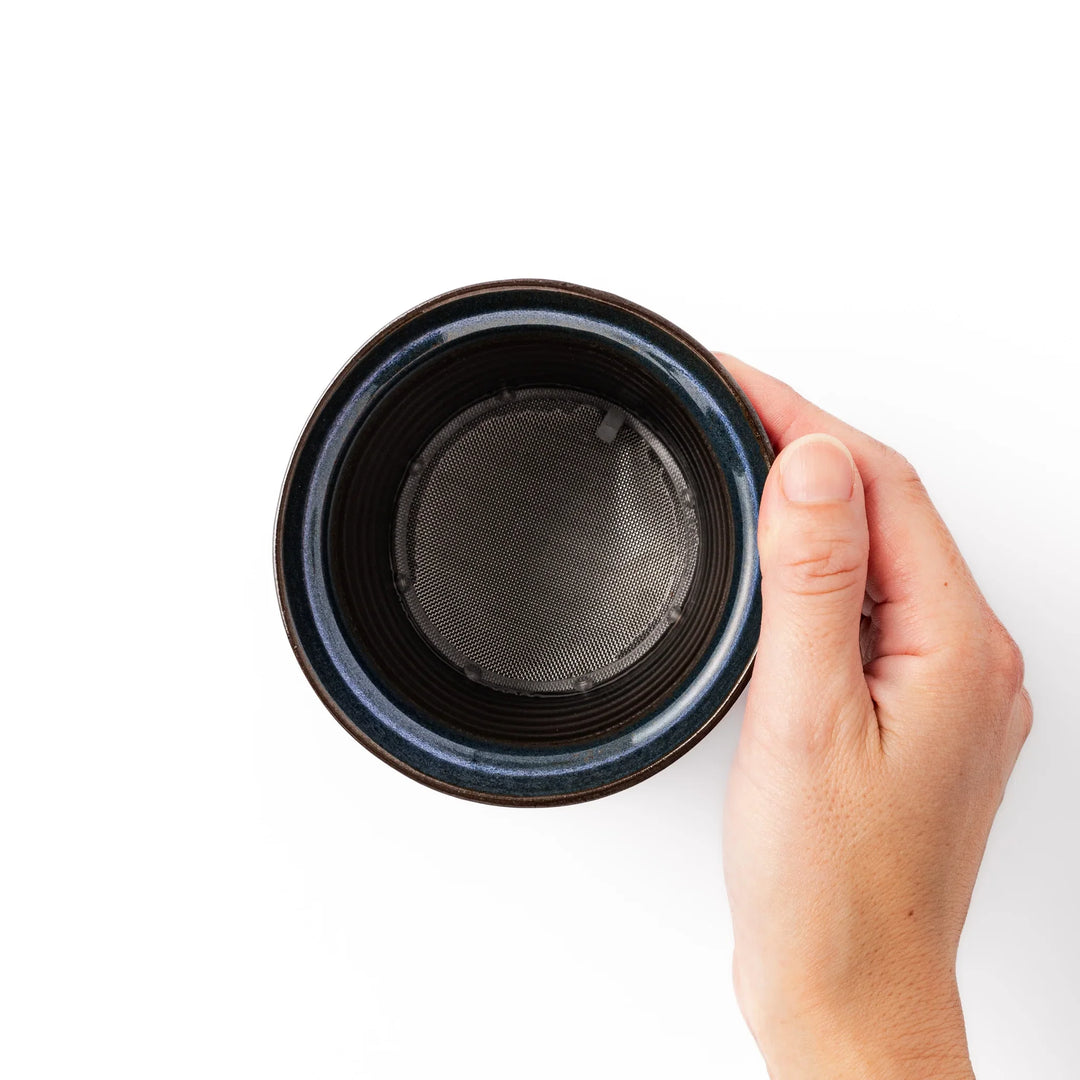 Handcrafted ceramic coffee dripper in earthy brown and blue glaze with detachable fine mesh filter, designed for single-serve brewing.