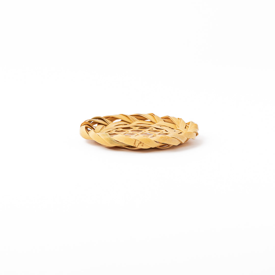 A round handwoven bamboo drink coaster showcasing a traditional star pattern weave and a braided natural fiber border