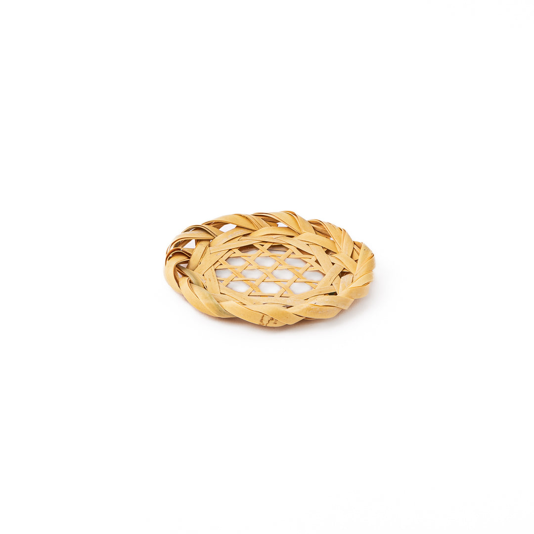 A round handwoven bamboo drink coaster showcasing a traditional star pattern weave and a braided natural fiber border