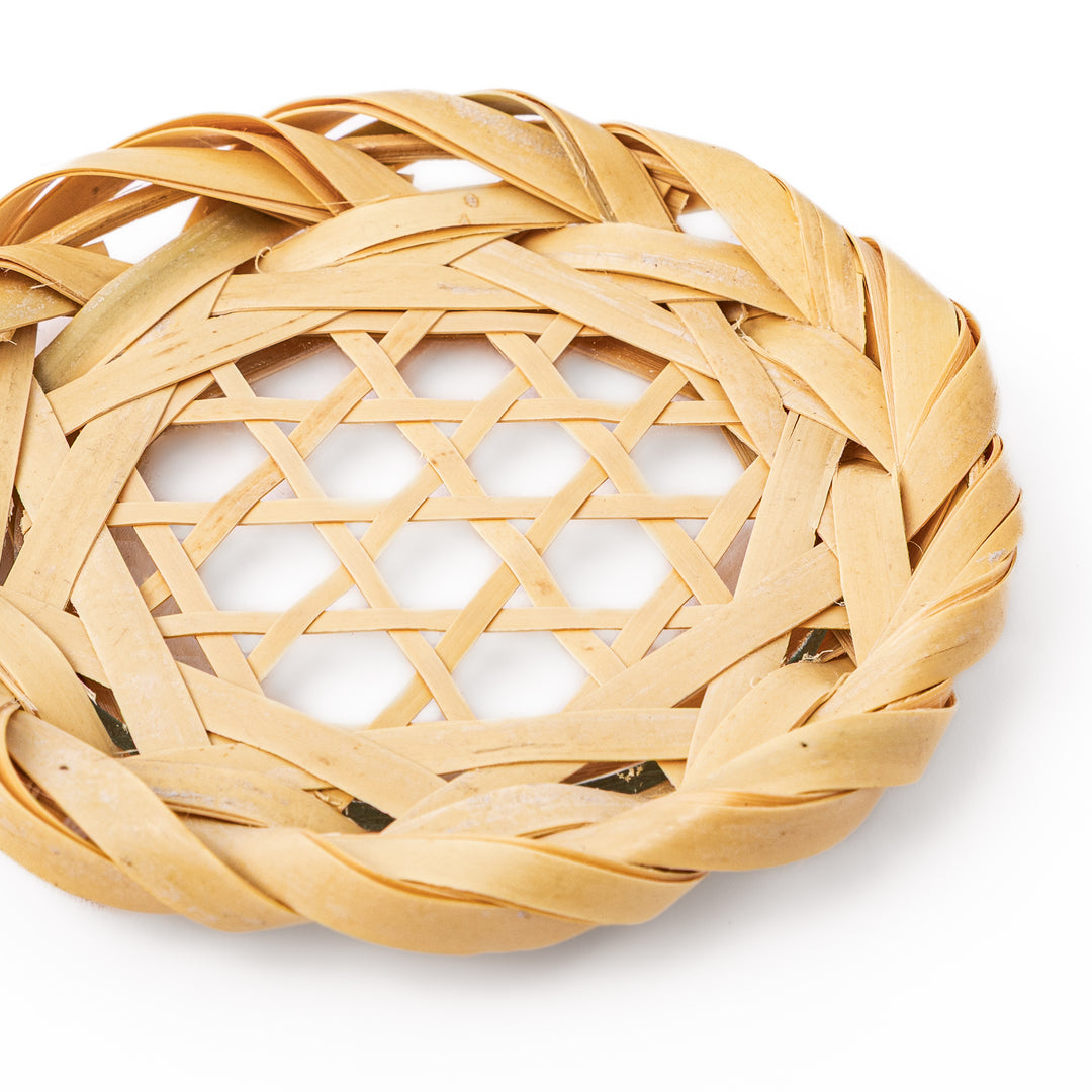 A round handwoven bamboo drink coaster showcasing a traditional star pattern weave and a braided natural fiber border