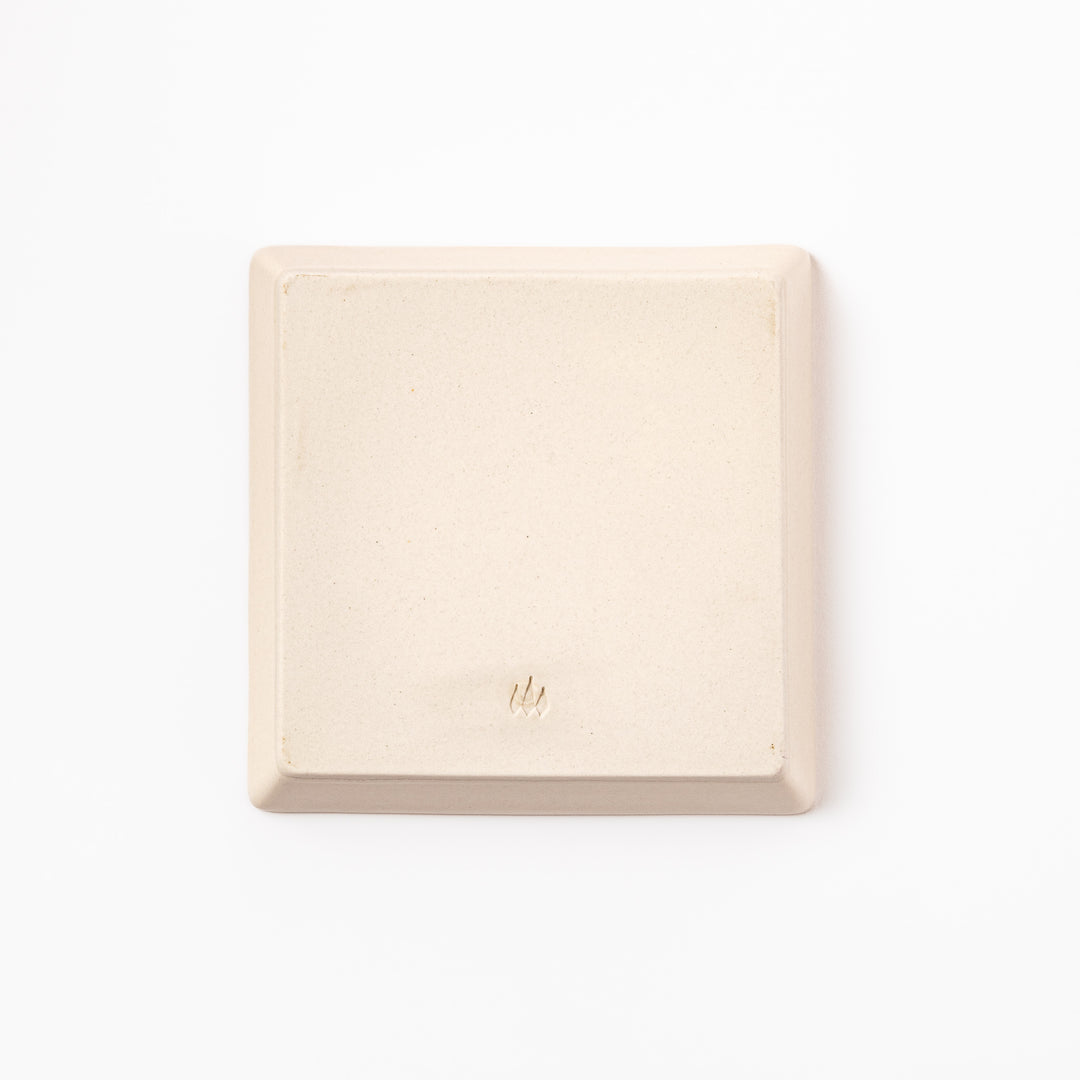 Square beige plate featuring a playful black cat chasing a butterfly, with paw prints and a dotted flight path.