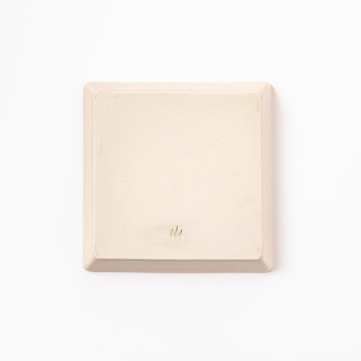 Square beige plate featuring a playful black cat chasing a butterfly, with paw prints and a dotted flight path.