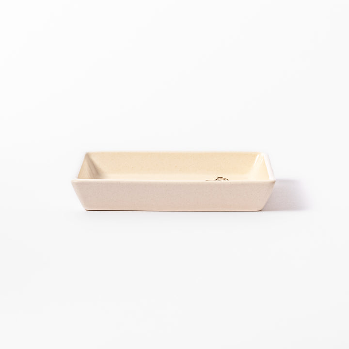 Beige square plate featuring a tabby cat chasing a butterfly with dotted trail and small paw prints.