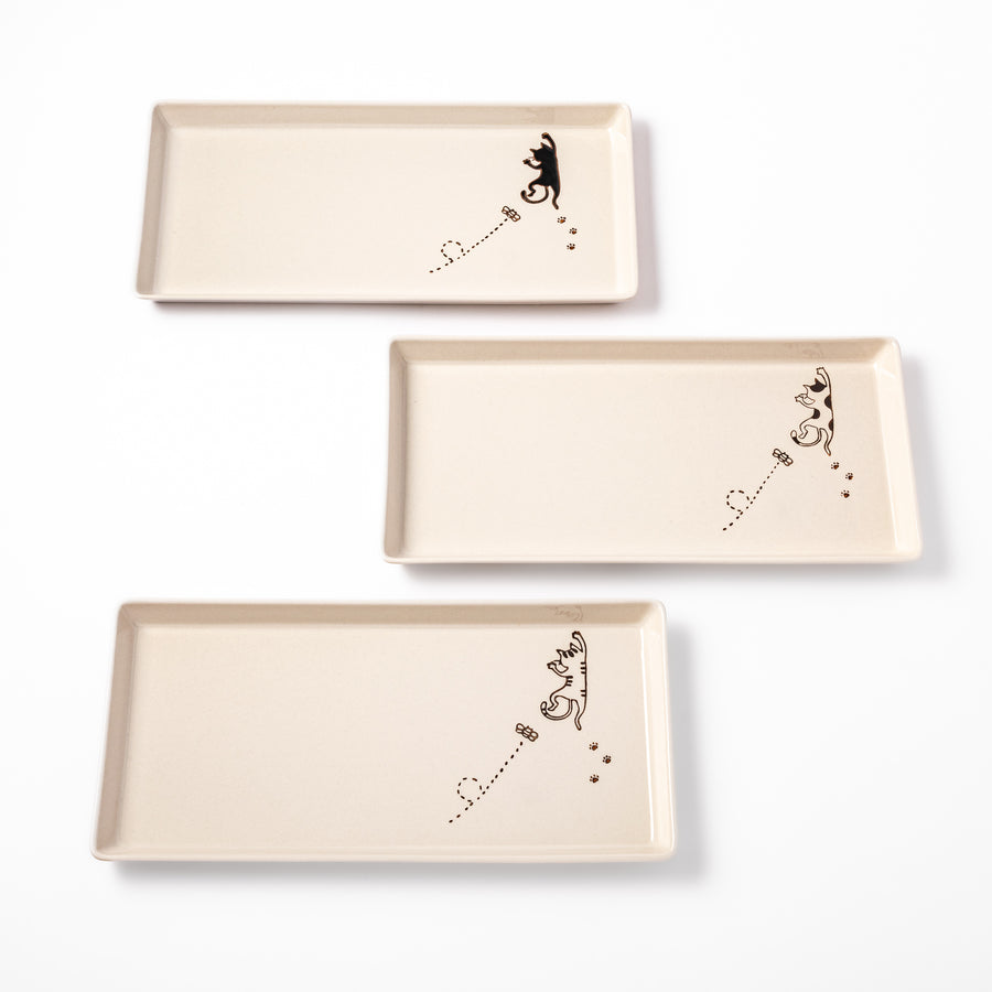 Set of beige rectangular ceramic plates featuring playful black, calico, and tabby cat illustrations with paw prints and butterflies.