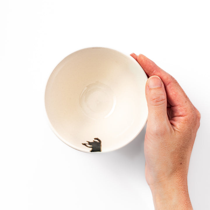 Cream-colored rice bowl with a black hanging cat, butterfly, and playful paw prints on the outside and inner rim.