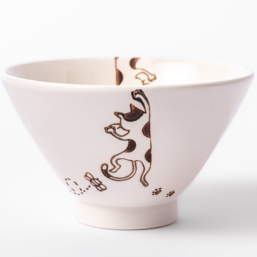 Cream-colored rice bowl with a calico hanging cat, butterfly, and playful paw prints on the outside and inner rim.